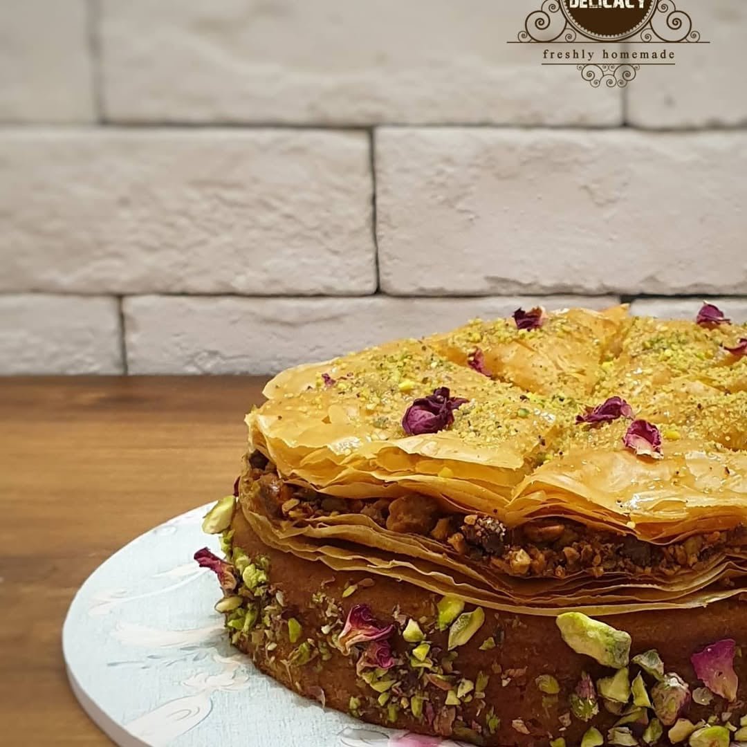 Pistachio cake topped with crisp baklava, pistachios and rose petals